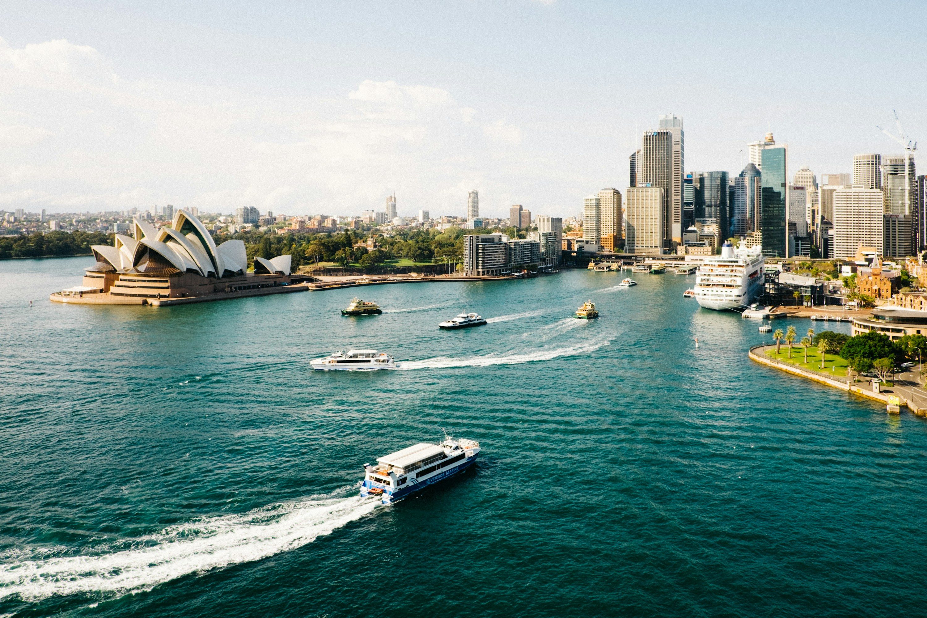 Sydney Harbour in bright daylight with ferries leaving white wakes
